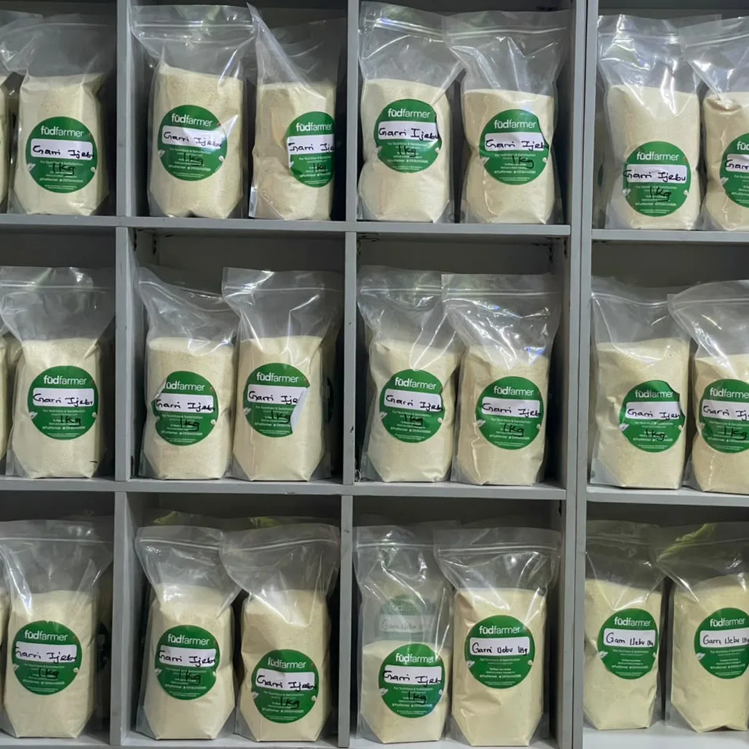 Shelves stacked with 1kg bags of fudfarmer-branded Garri Ijebu, each hand-labelled, in a retail store.